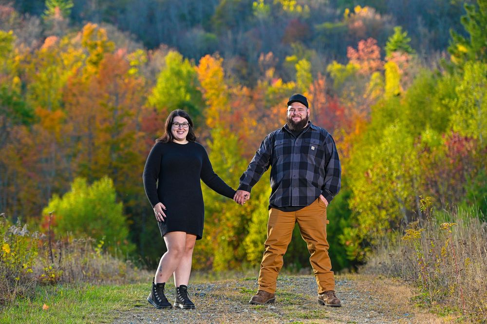 Family and dog walking together on a scenic autumn trail surrounded by vibrant fall foliage.