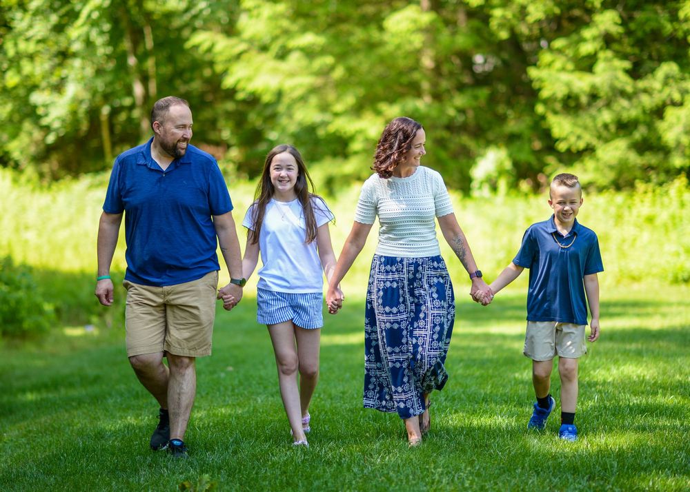 Family members walking together on green grass during a summer day in the park.