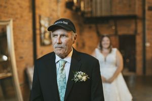 A person in a black baseball cap and tie stands in front of exposed brick walls at an indoor venue.