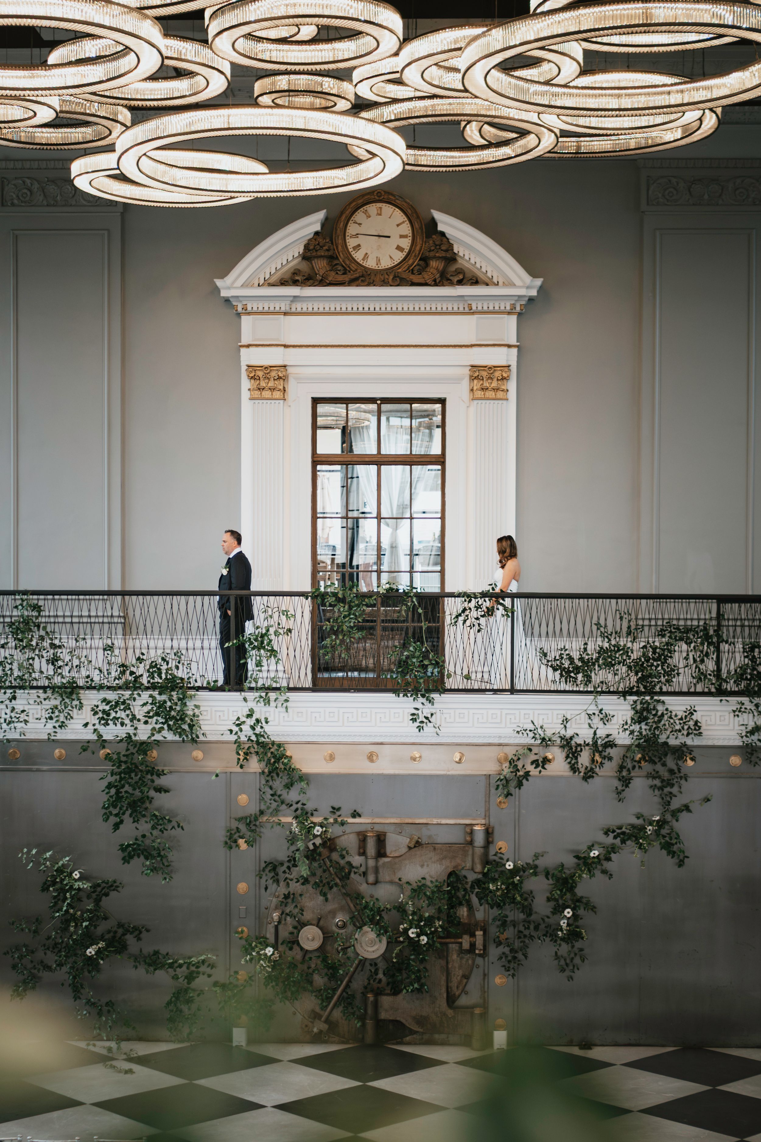Modern ballroom interior with spiral ceiling lights, indoor plants, and a checkered floor pattern creates an elegant ambiance.