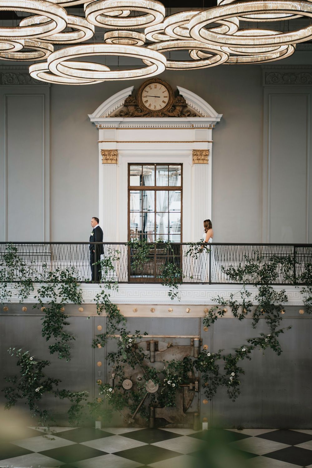 Modern ballroom interior with spiral ceiling lights, indoor plants, and a checkered floor pattern creates an elegant ambiance.