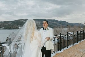 A winter wedding celebration overlooking a snowy mountain landscape with an ornate railing in the foreground.