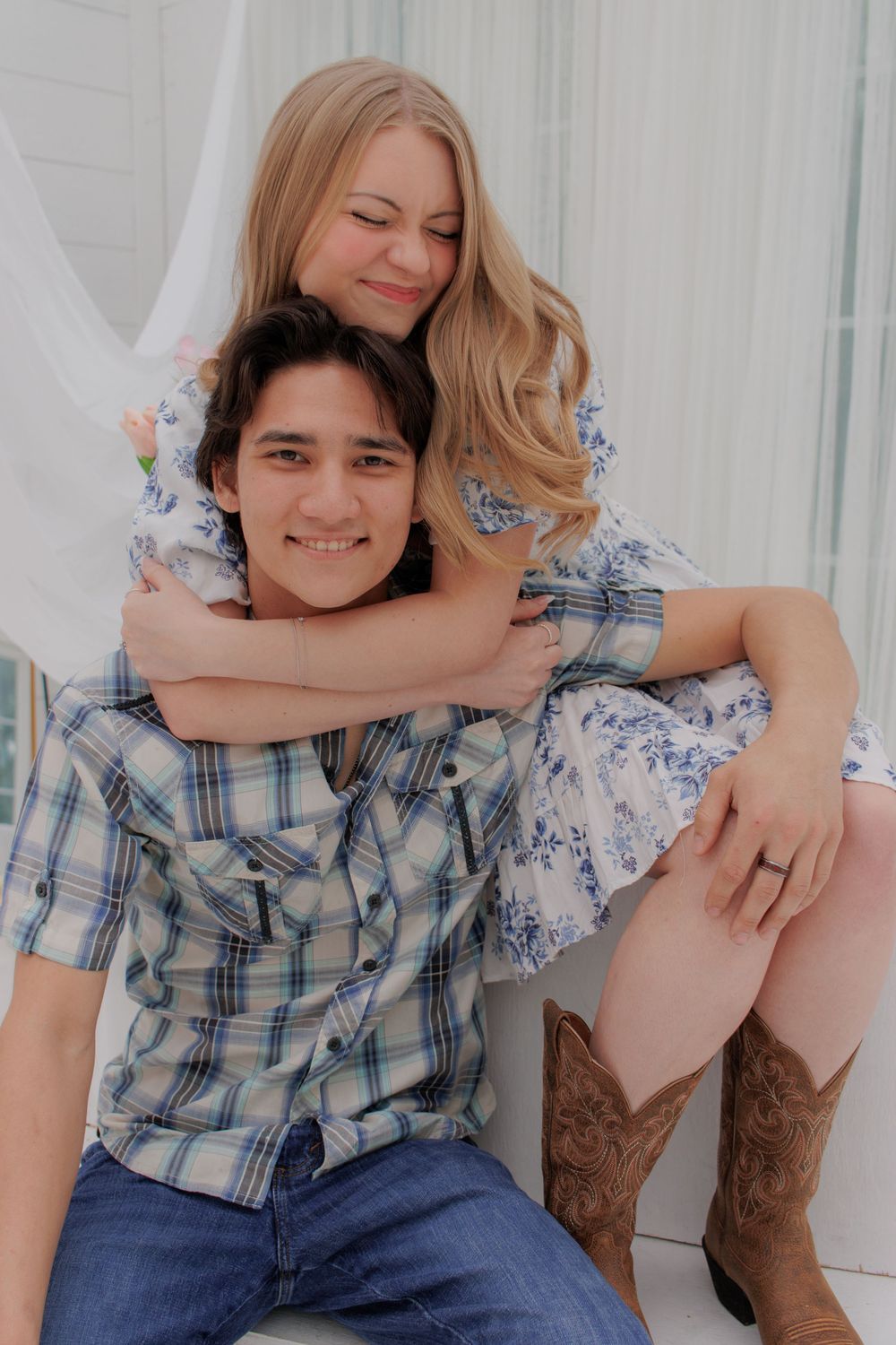 Couple in casual attire sharing intimate moments against white backdrop.