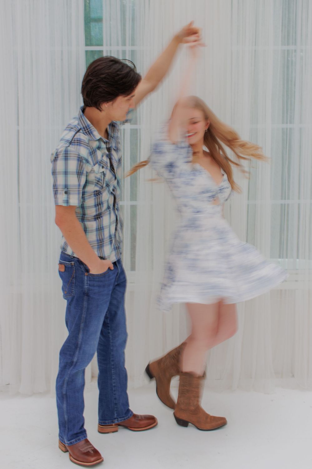 Dancing couple in plaid shirt and floral dress against white backdrop.