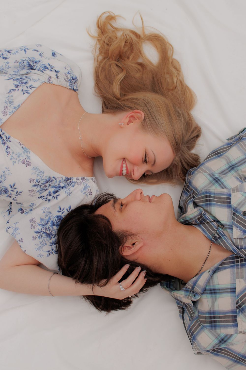 Intimate couple portrait with plaid shirt and floral dress on white background.