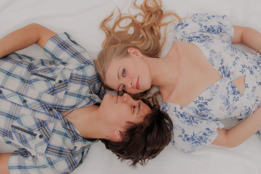 Romantic couple lying close together wearing plaid and floral outfits.