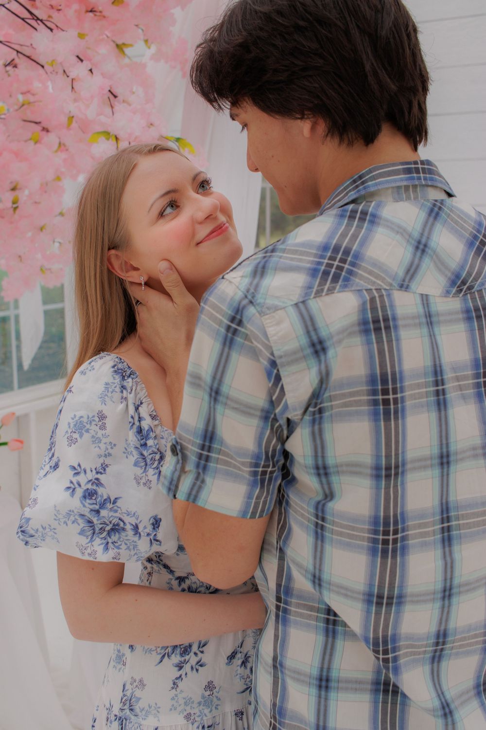 A young couple embracing affectionately in a floral setting.