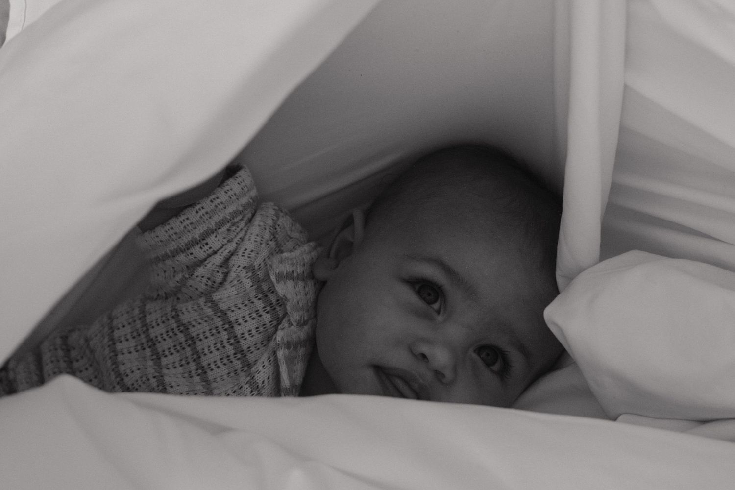 The classic black and white photograph showing a baby lying in a white sheet at the beach.
