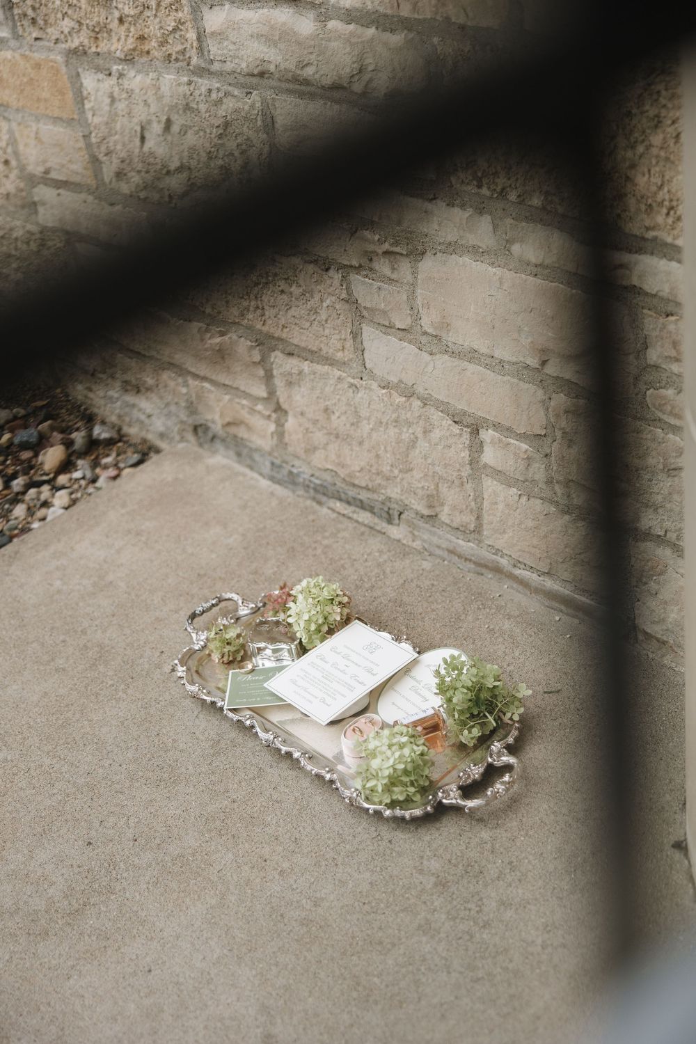 Scattered white flowers and paper lying on a concrete ground with dramatic diagonal shadows cast across the surface.