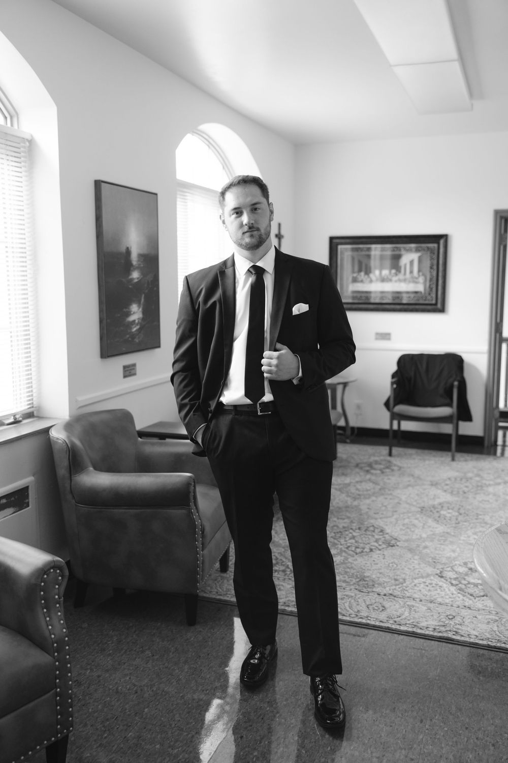 A black and white photo series showing a person in a dark suit standing in an elegant room with patterned carpeting.