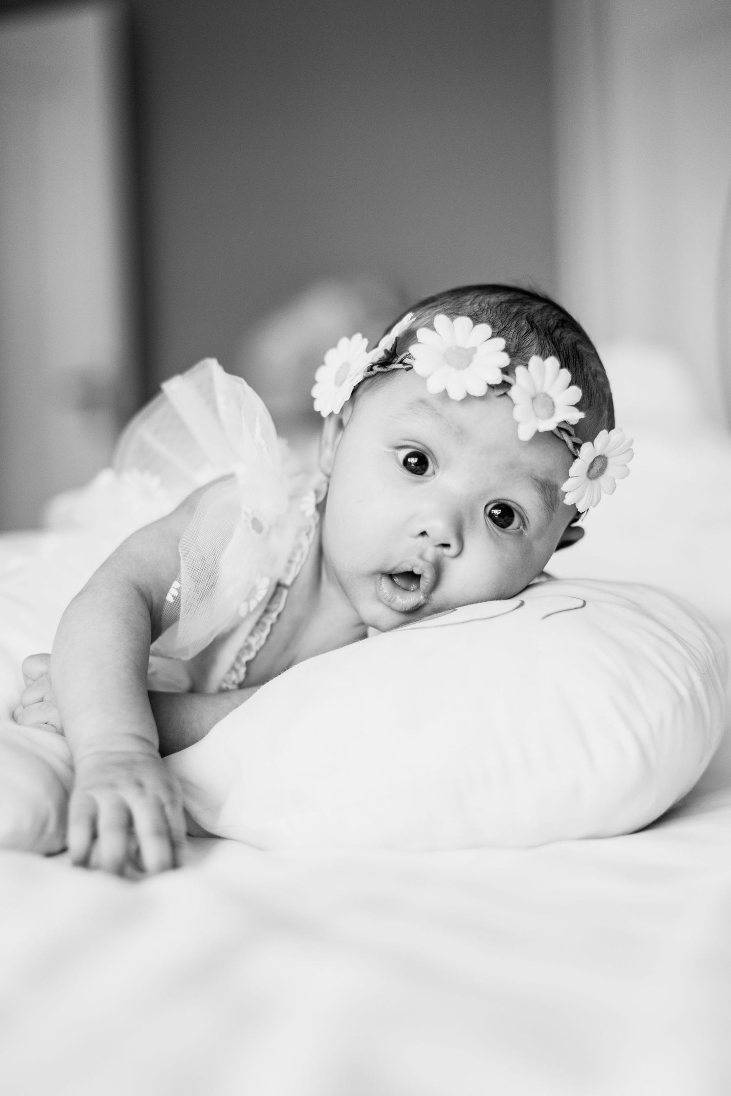 Sweet baby portrait series with white flowers and soft bedding.