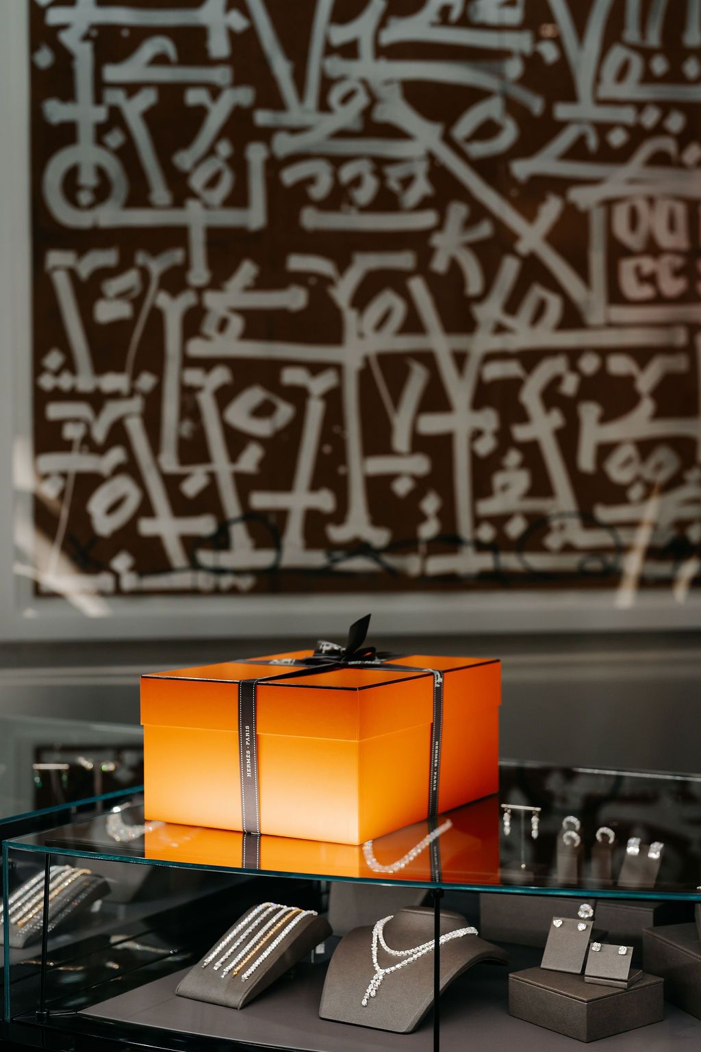 Orange Nike shoe boxes arranged on a dark surface with black and white graffiti wall art in the background.