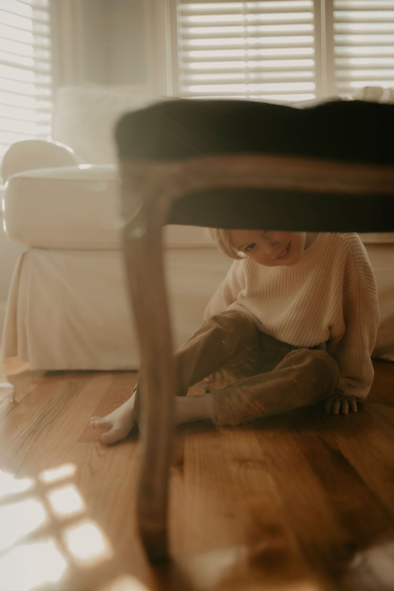 A person sits on a hardwood floor near a window with sunlight streaming in, creating a warm, nostalgic atmosphere.