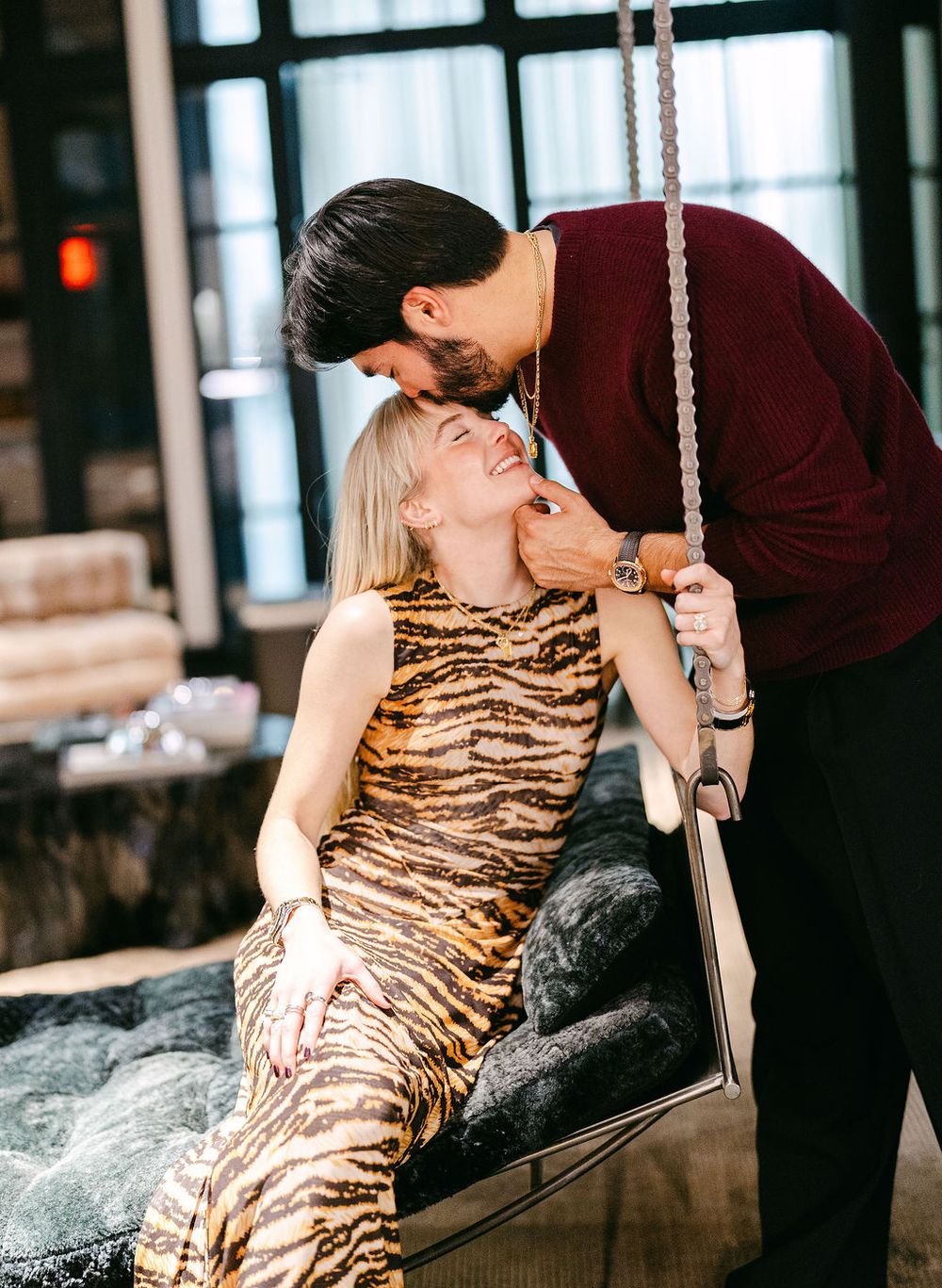 A romantic couple embraces in an elegant setting, with the woman wearing a striking tiger print dress.