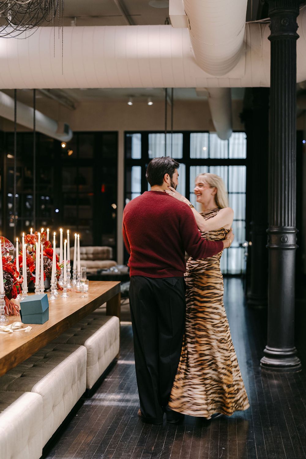 Couple sharing an intimate moment in an elegant venue with candlelit table and tiger-striped formal gown.