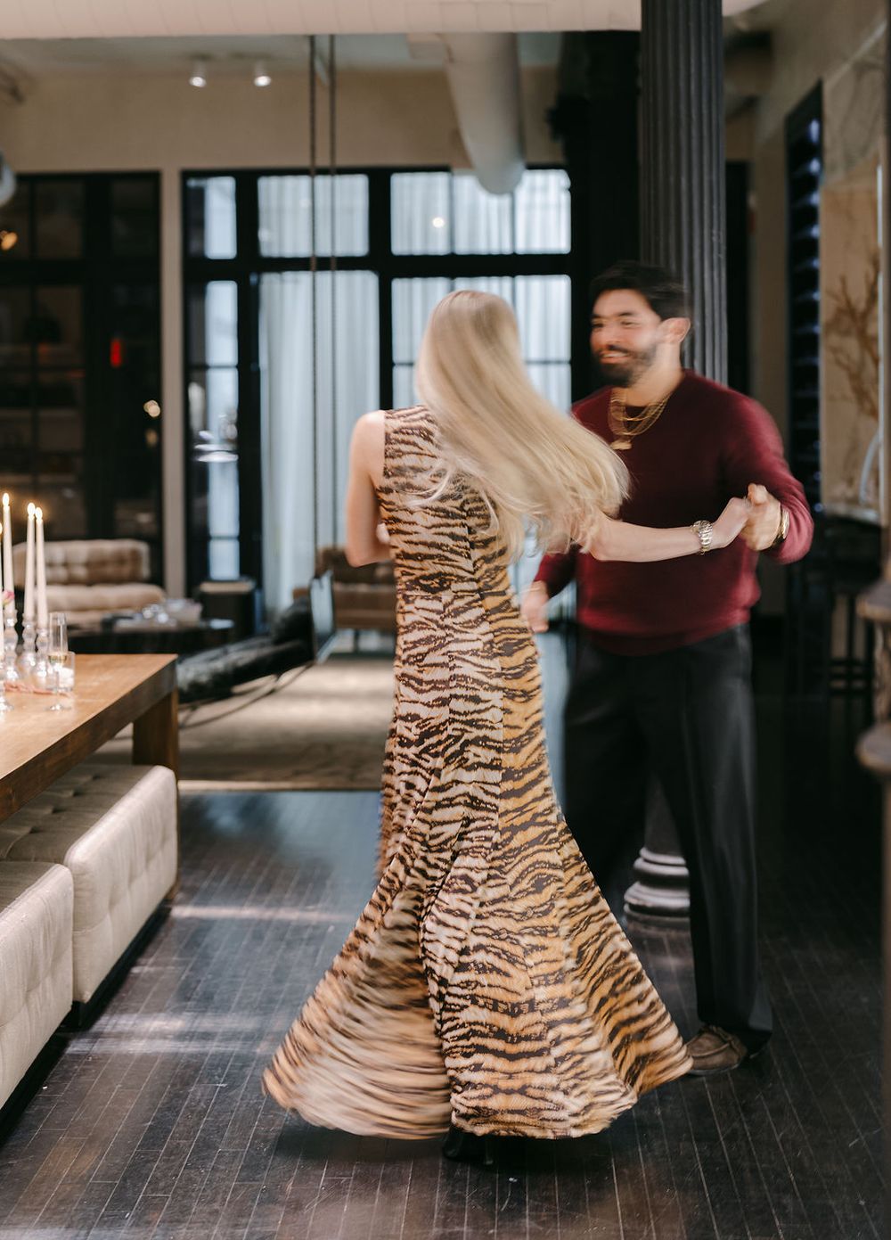Couple sharing an intimate moment in a modern interior space with large windows and dark floors.