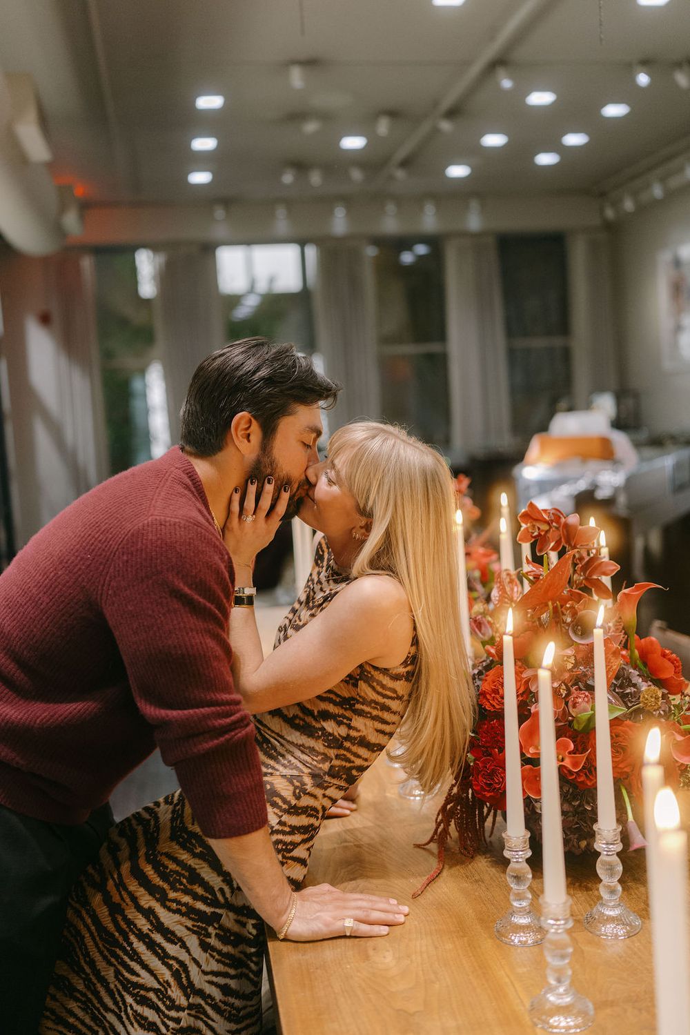 A romantic couple shares an intimate moment at a candlelit table decorated with autumn florals.
