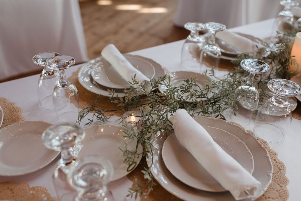 Elegant wedding table settings with white linens, crystal glassware, and delicate floral arrangements create a romantic atmosphere.