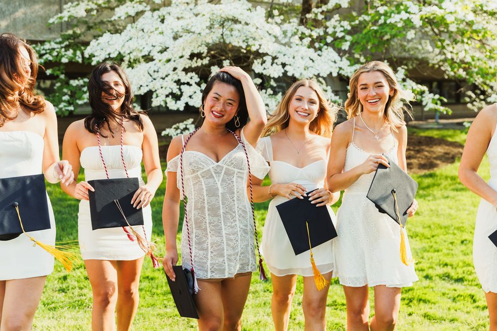 Group of friends in white dresses posing together during an outdoor photoshoot.