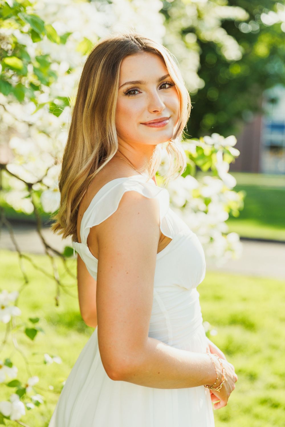 Spring portrait session in a white dress surrounded by blooming dogwood flowers.