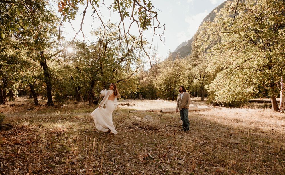 A couple shares a romantic moment in a rustic outdoor setting with mountains and autumn trees in the background.