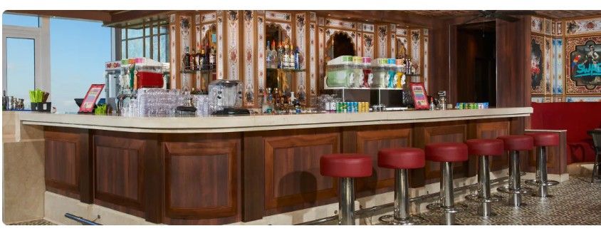 Modern hotel bar interior with red bar stools and warm lighting creates an inviting atmosphere for guests.
