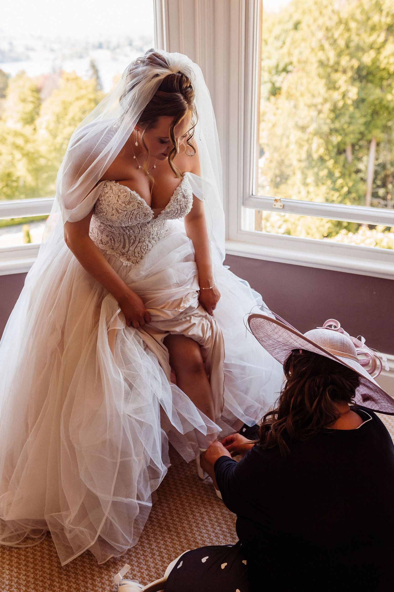 A bride in a white wedding dress and veil adjusts her shoe while sitting by a window in a series of sequential photos.