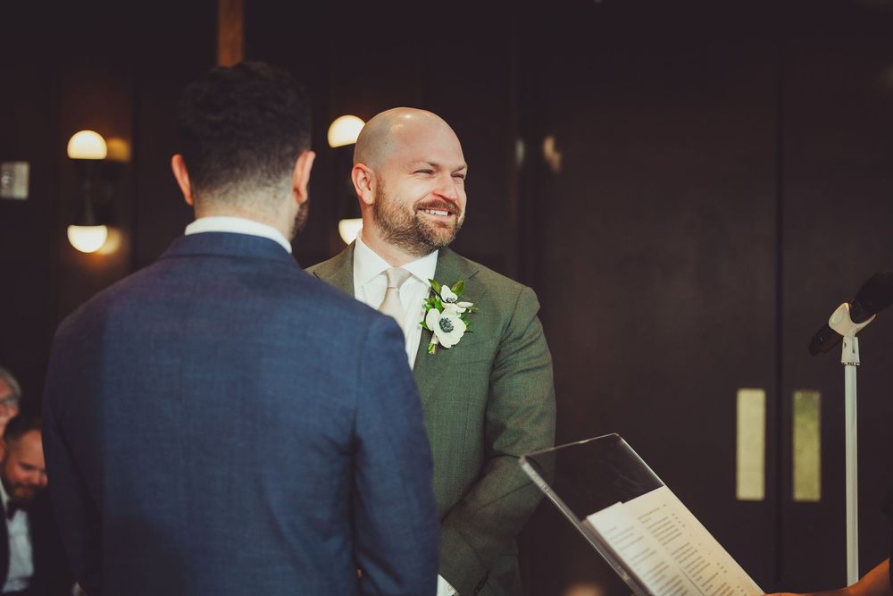 Two people share a joyful moment during a wedding ceremony while holding papers and exchanging vows.