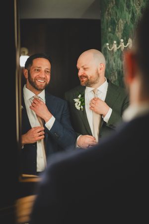 Same-sex couple in formal attire share a candid laughing moment after they have become husband and husband