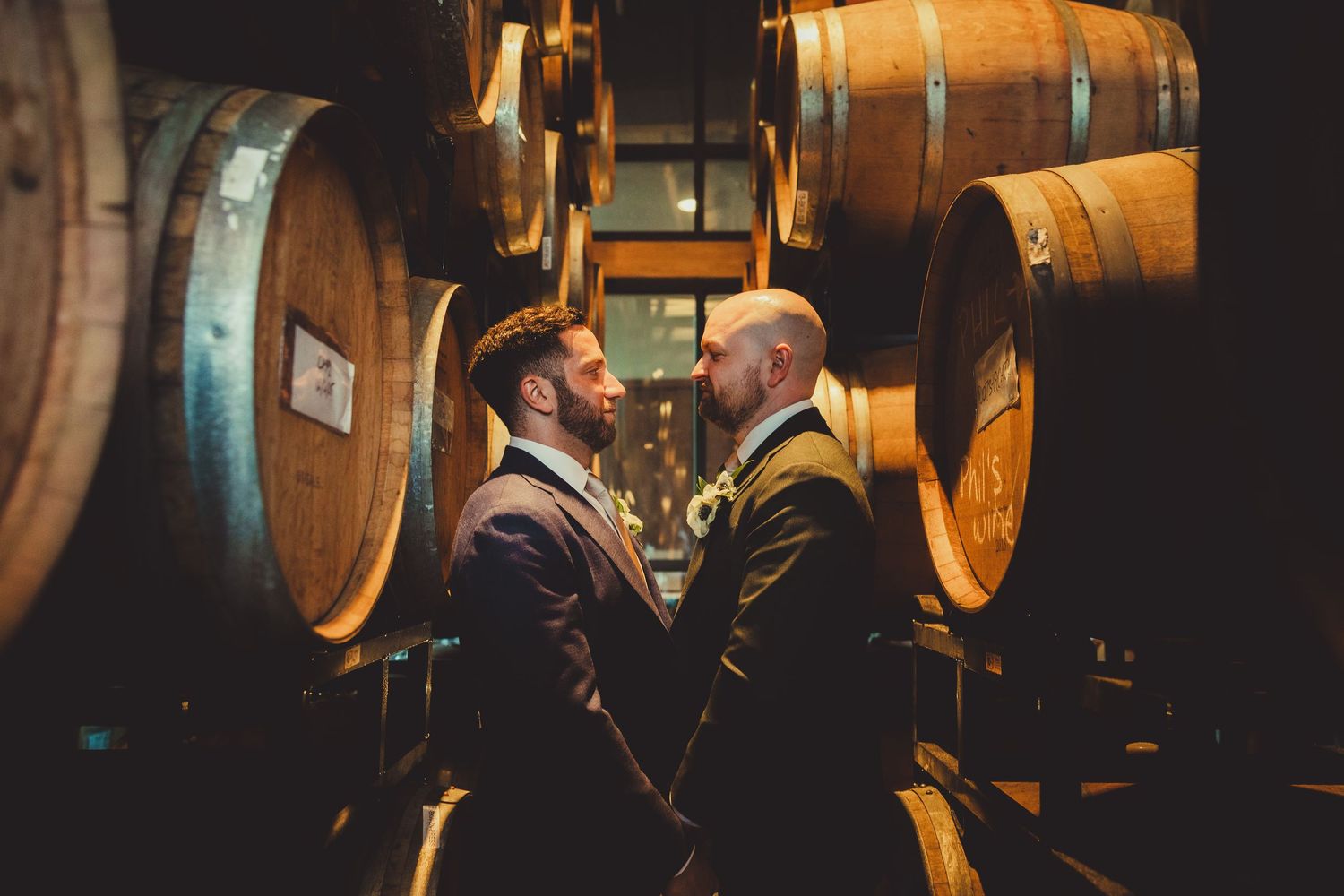 Wine barrels stacked in a dimly lit cellar with warm lighting creating an atmospheric ambiance.
