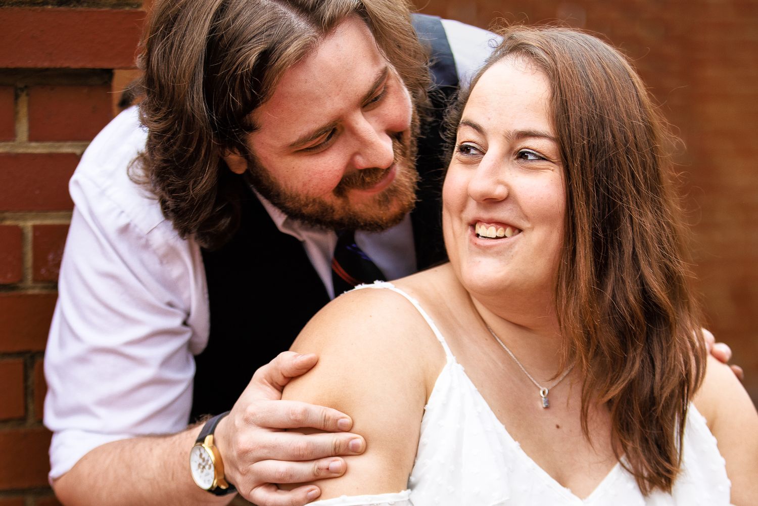 A romantic couple shares intimate moments in a series of candid photographs against a brick wall background.