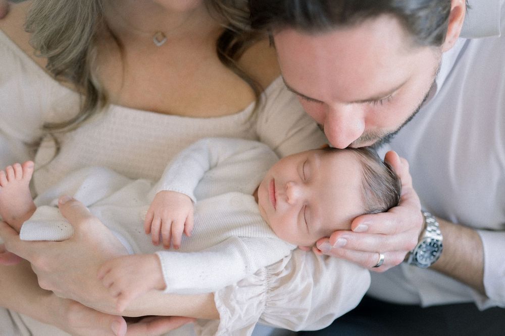 A parent gently kisses their newborn baby's tiny feet while holding them in a tender moment taken by a northern virginia newborn photographe