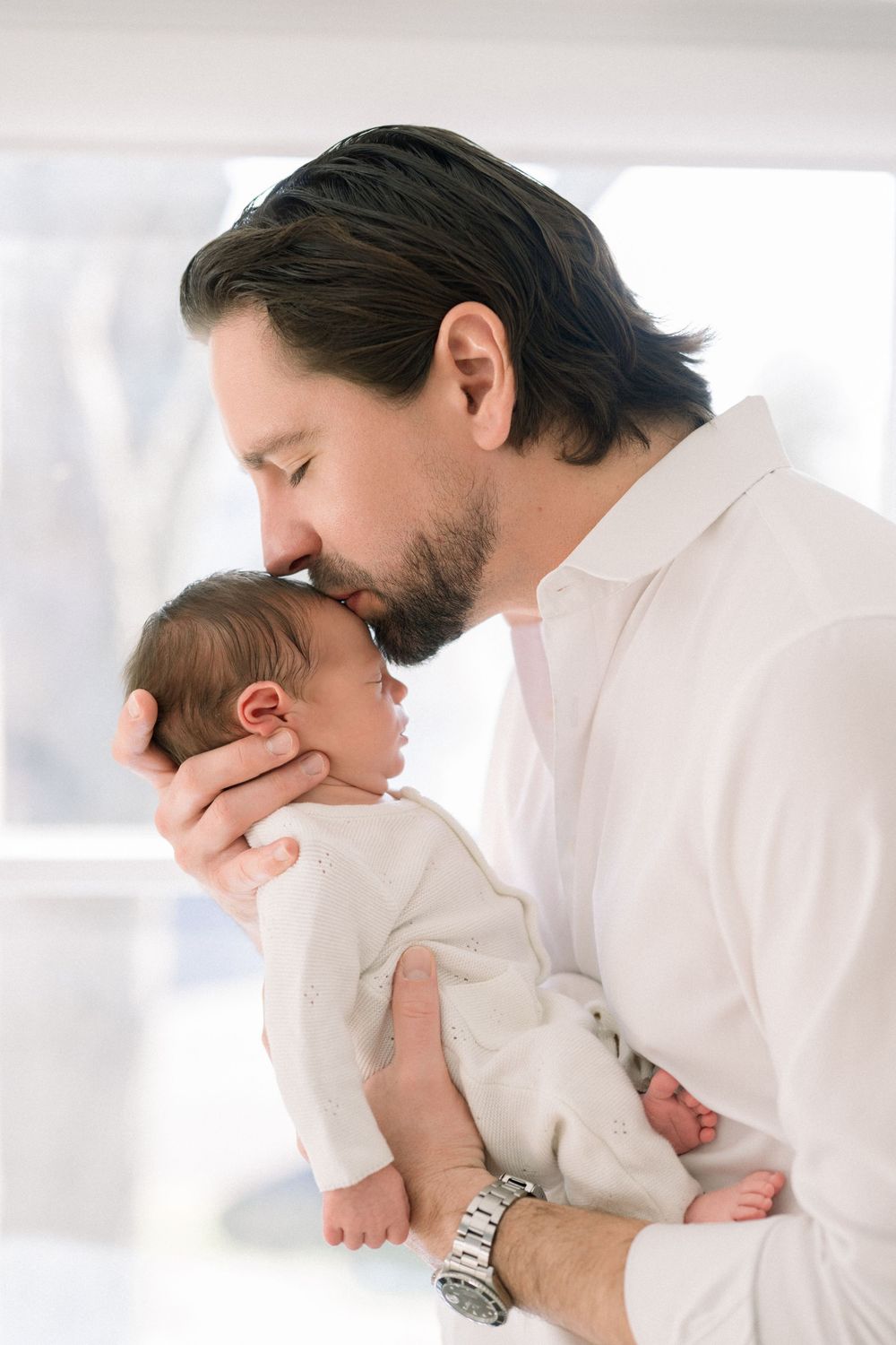 a dad kissing his newborn at their in-home newborn session
