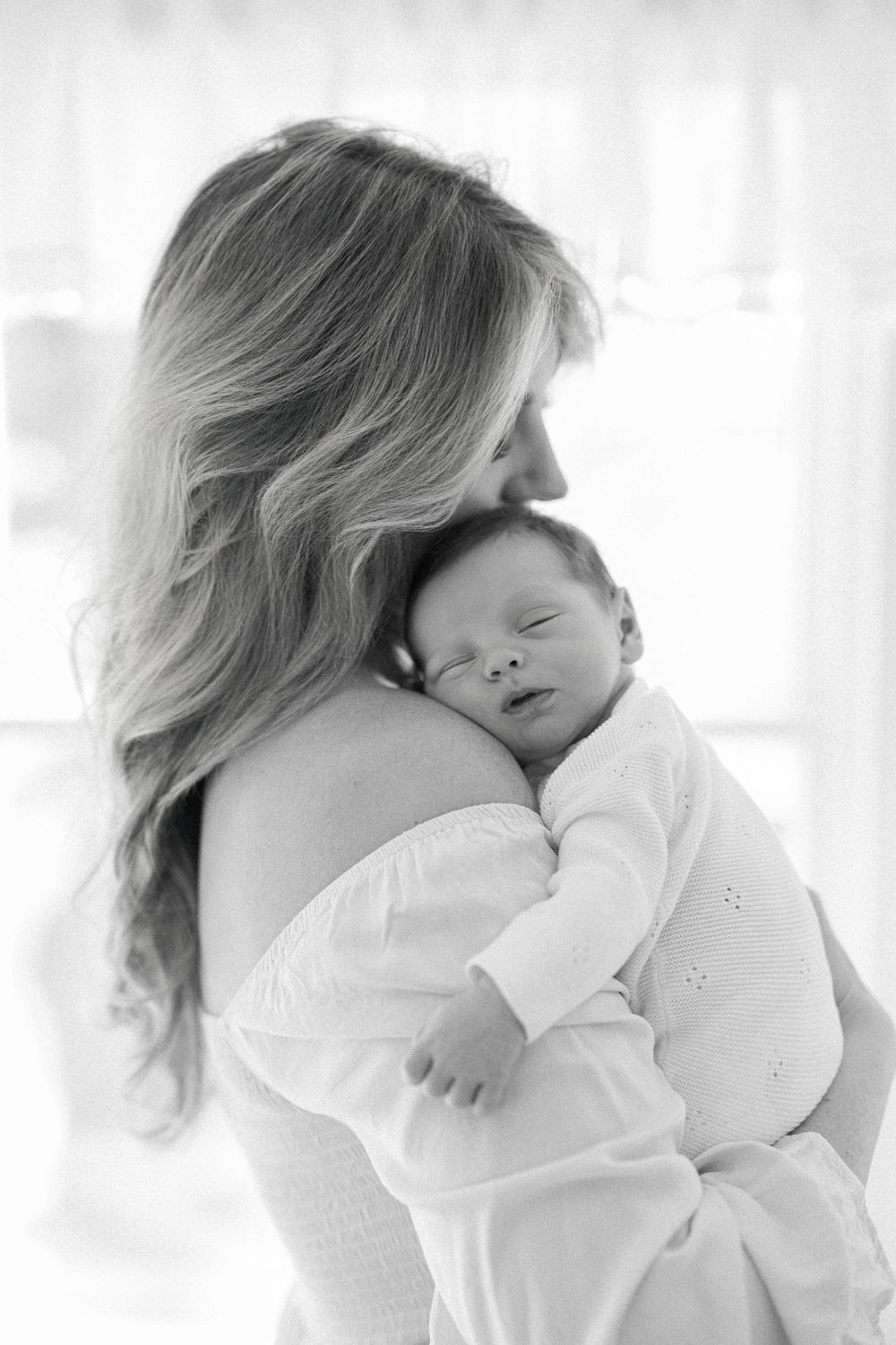 A tender black and white photo of a mother and her baby at an in-home newborn photoshoot in washington dc