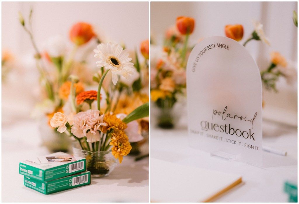 Soft peach and orange floral centerpieces with scattered greenery adorn a wedding reception table with elegant place settings.