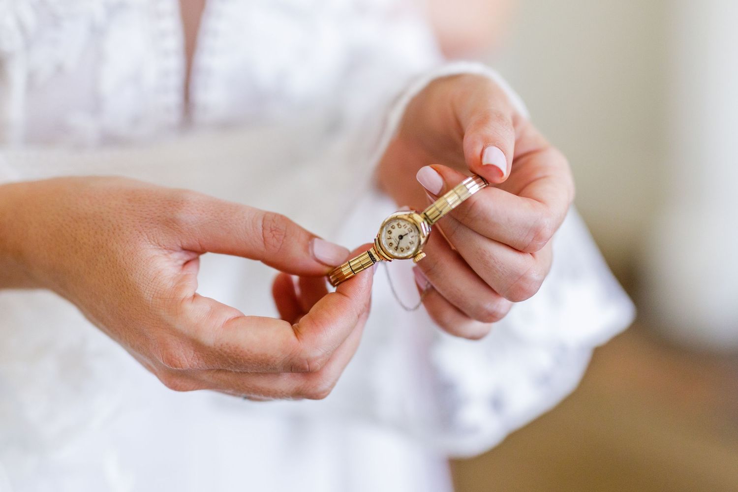 Hands holding a delicate gold key with ornate details against a soft white background.