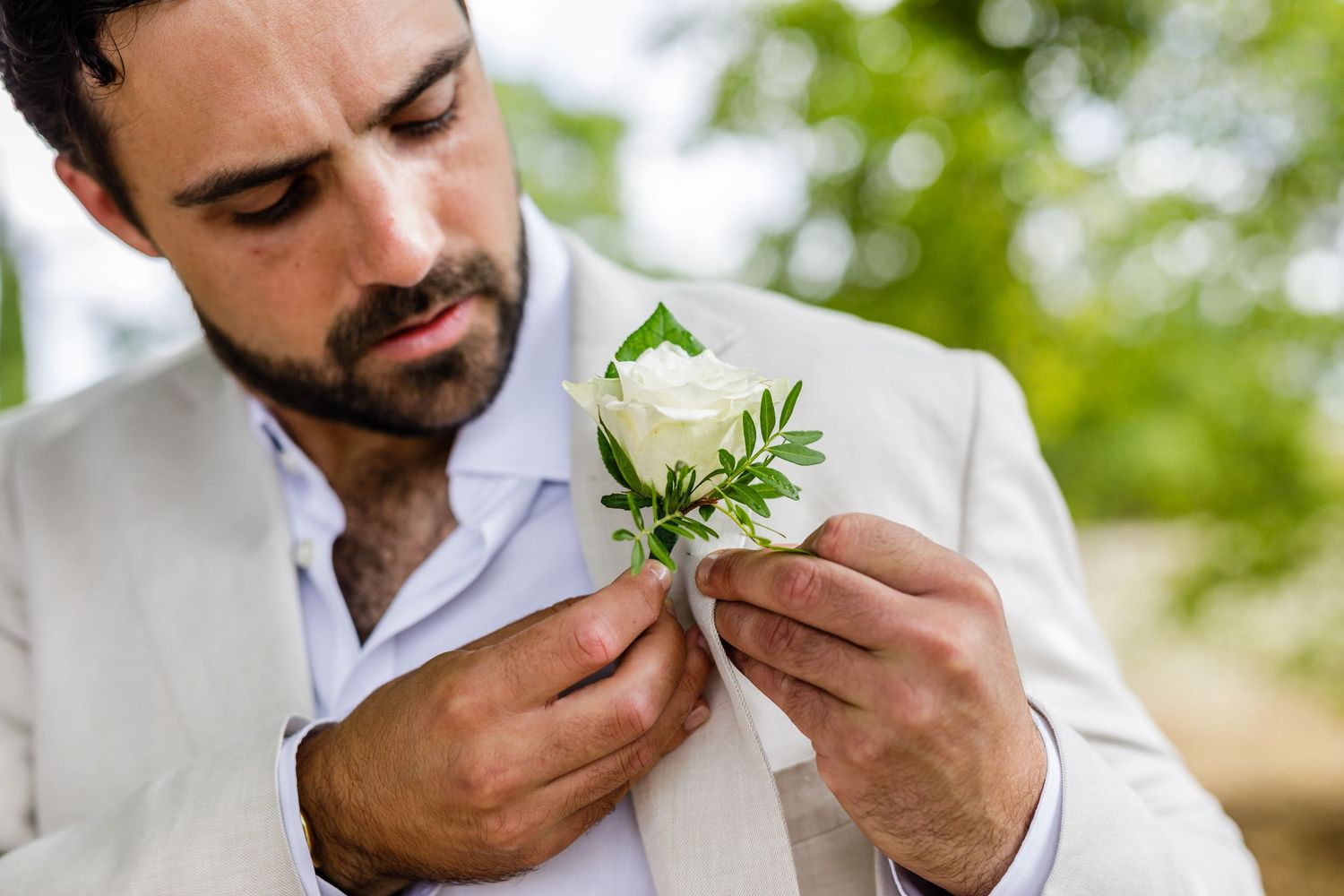 Man in white shirt smelling fresh herbs and enjoying their aroma in a bright outdoor setting.