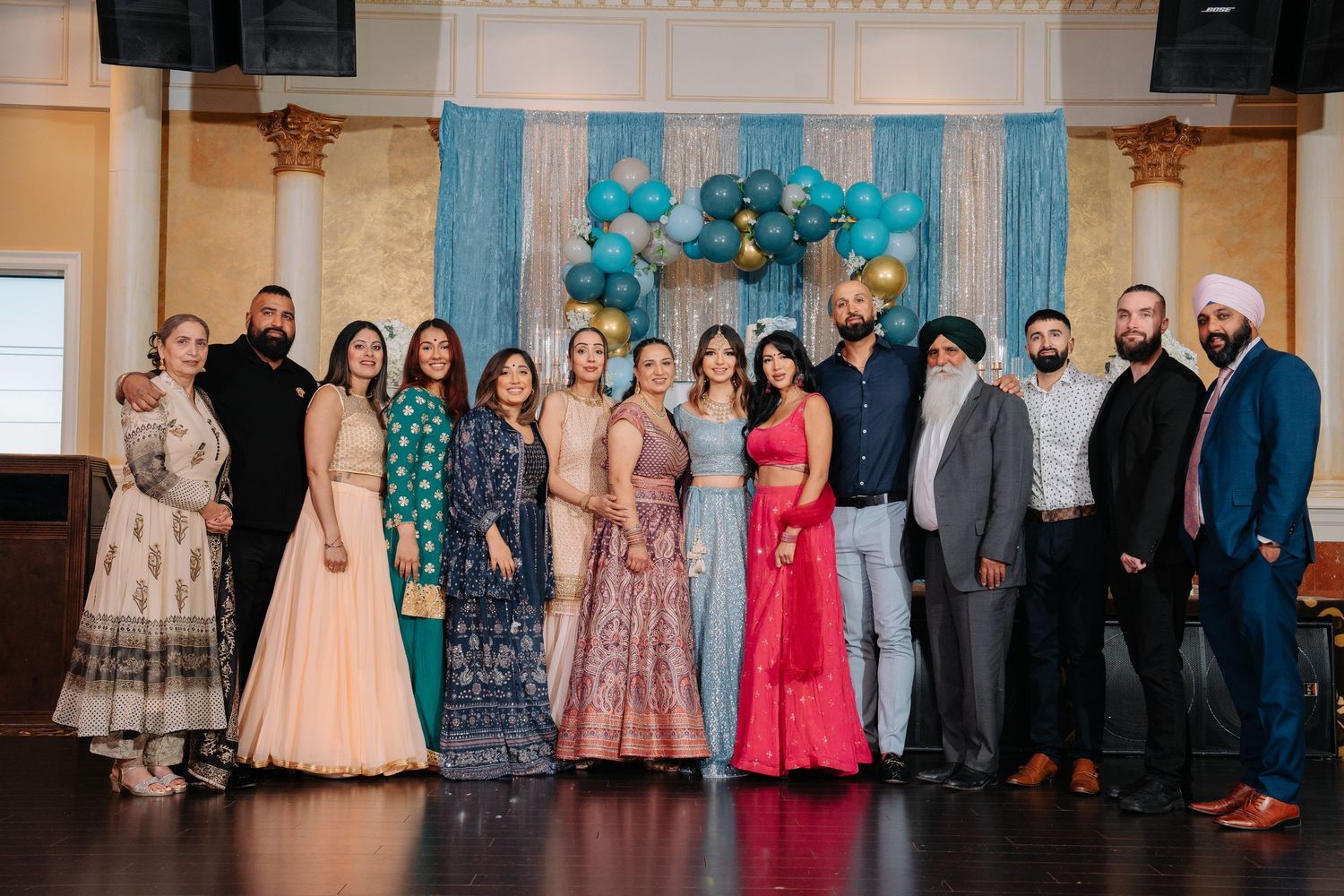 A group of people wearing formal attire and evening gowns pose together at a special event.