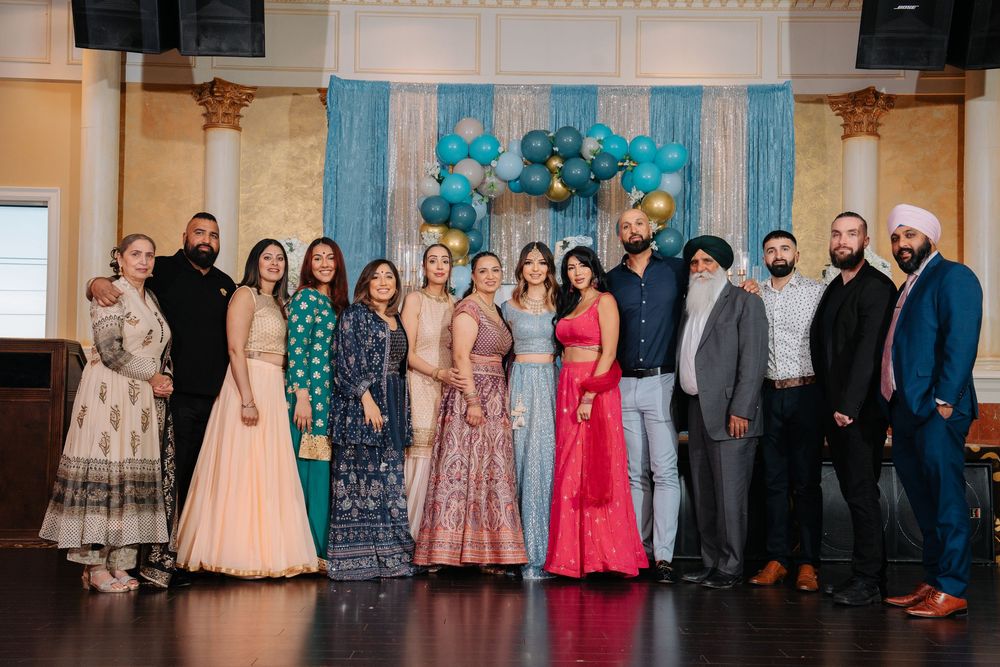 A group of people wearing formal attire and evening gowns pose together at a special event.