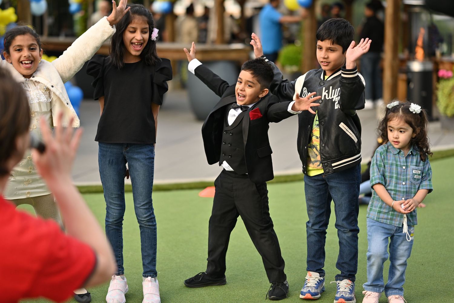 Children and adults participate in outdoor group activities and games on a sunny day.