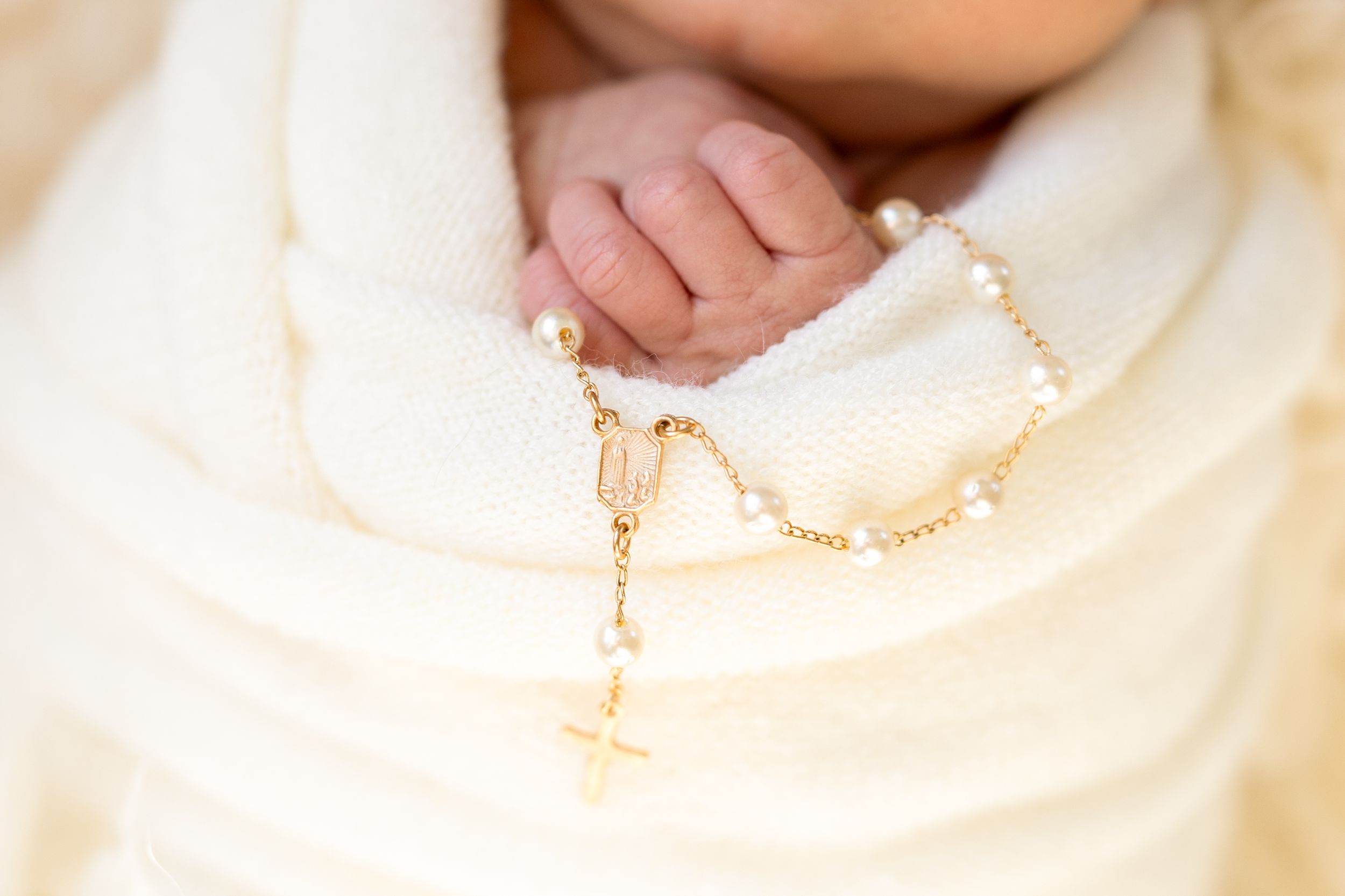 Delicate gold chain necklace with tiny beads and pearls displayed on a light colored surface.