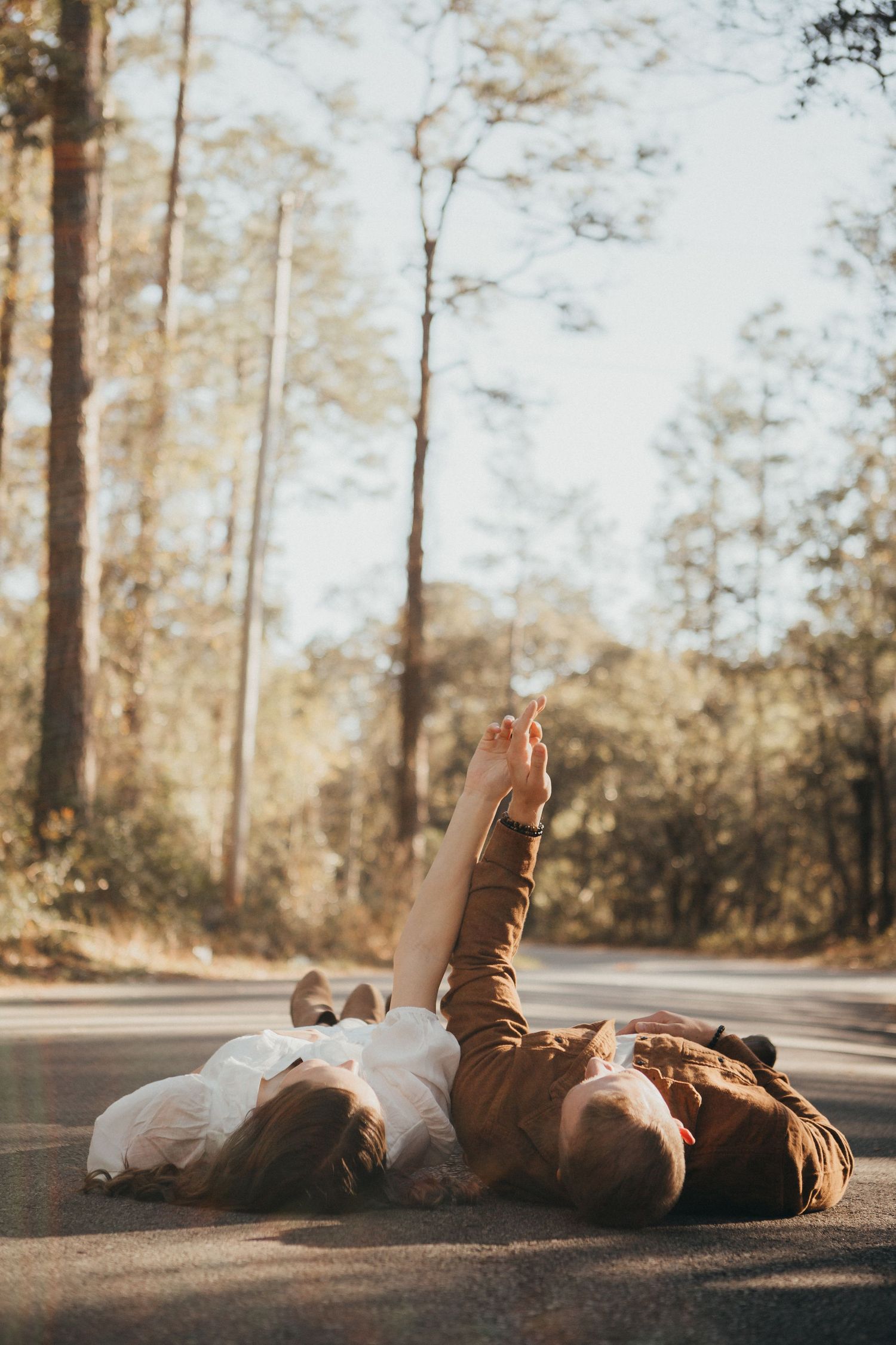 Couples photo session, a couple laying in middle of the road holding hands and looking at each other