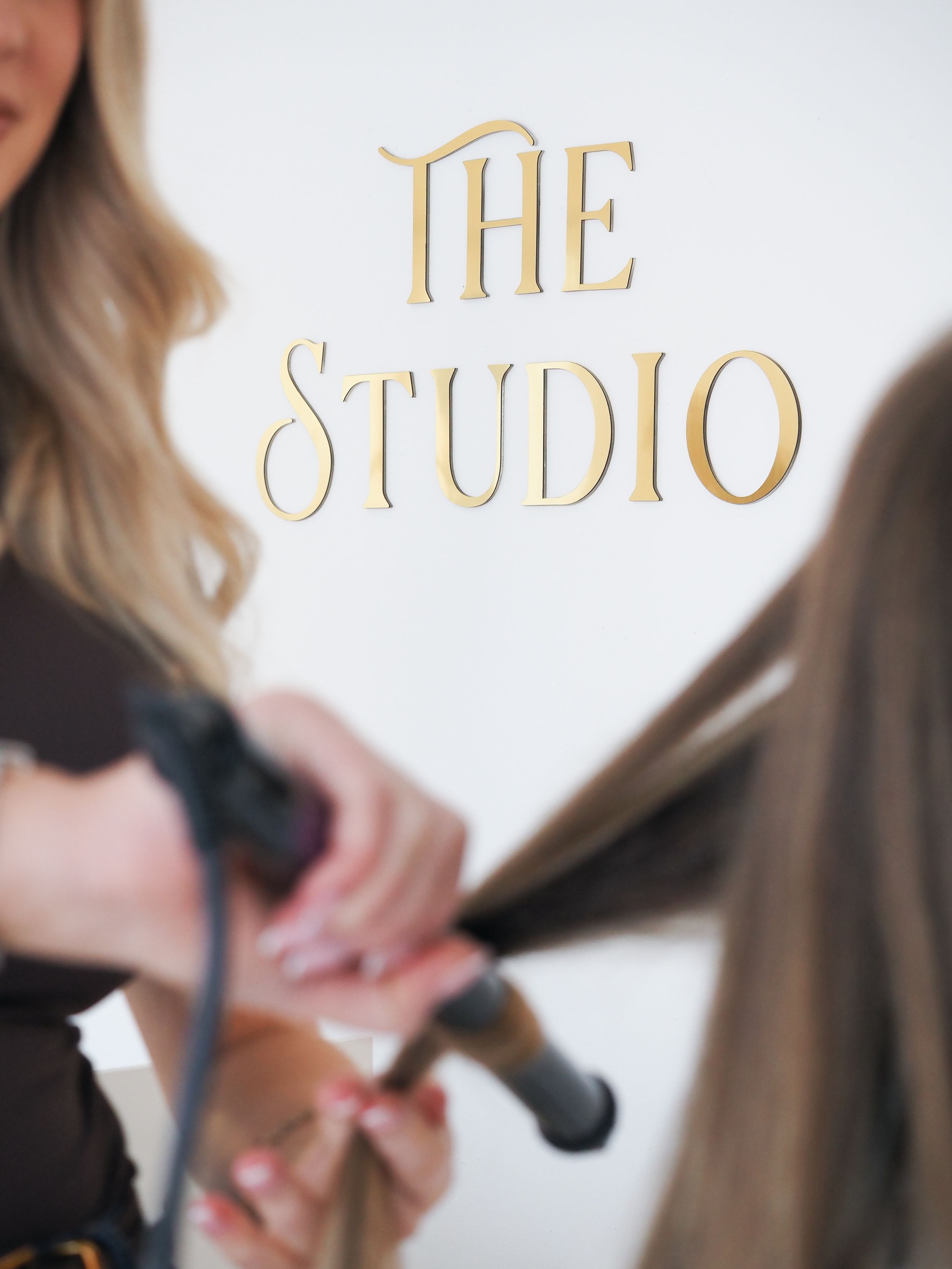 A stylist works on adjusting and styling long blonde hair in a professional salon setting.