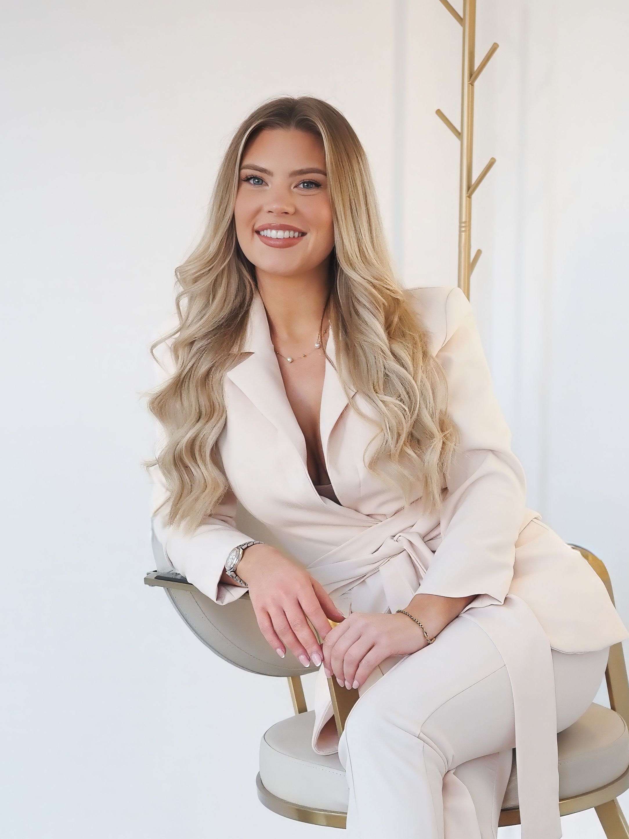 Professional lifestyle portrait series featuring a person in a cream-colored blazer sitting on a light gray chair against a white backdrop.