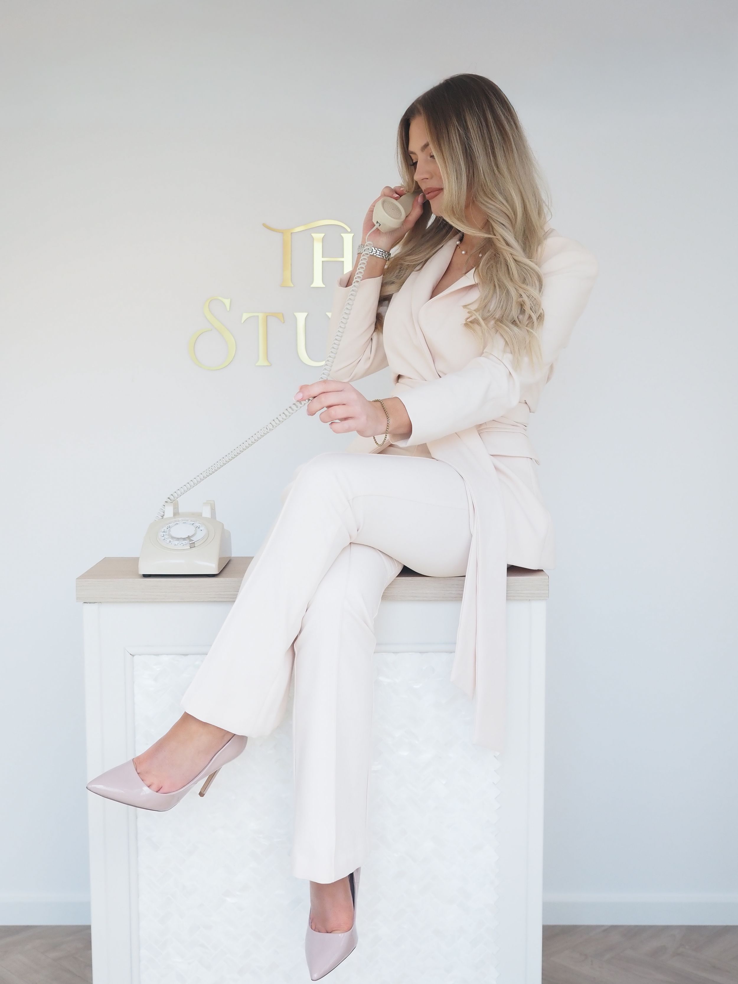 Professional lifestyle photo series showing a woman in a light pink blazer sitting elegantly on white furniture.