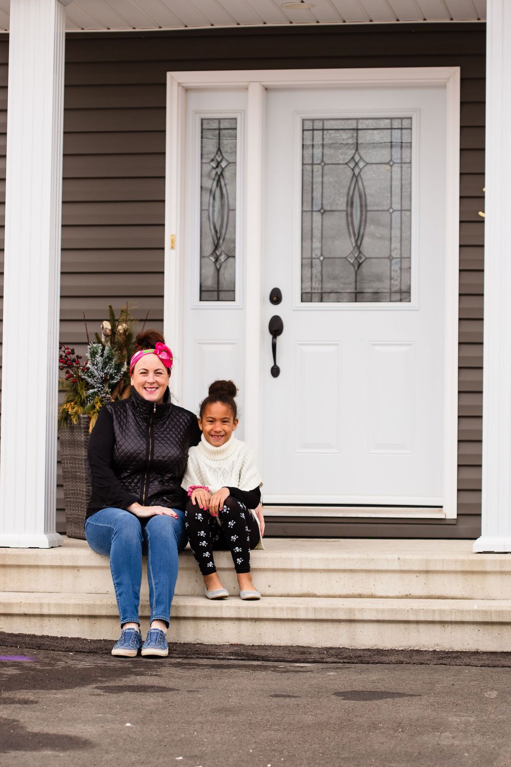 People sitting on a front porch with a black cat, enjoying a casual moment together.