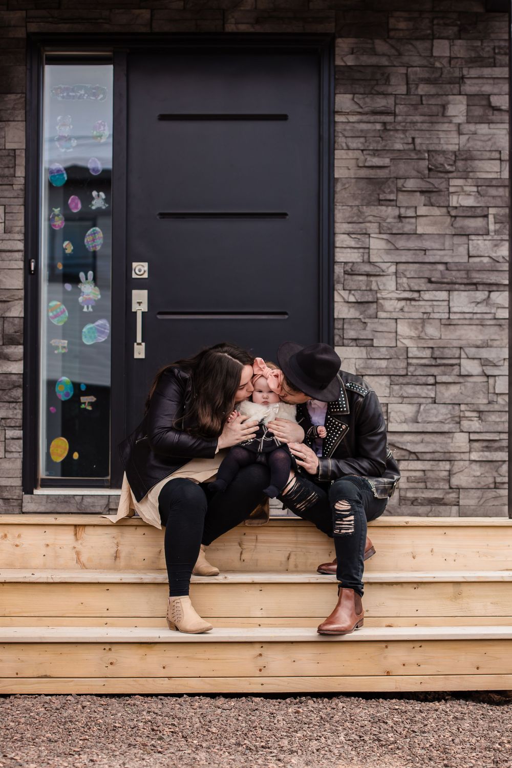 People relax on a wooden ledge against a stone wall with decorative stickers on the door.