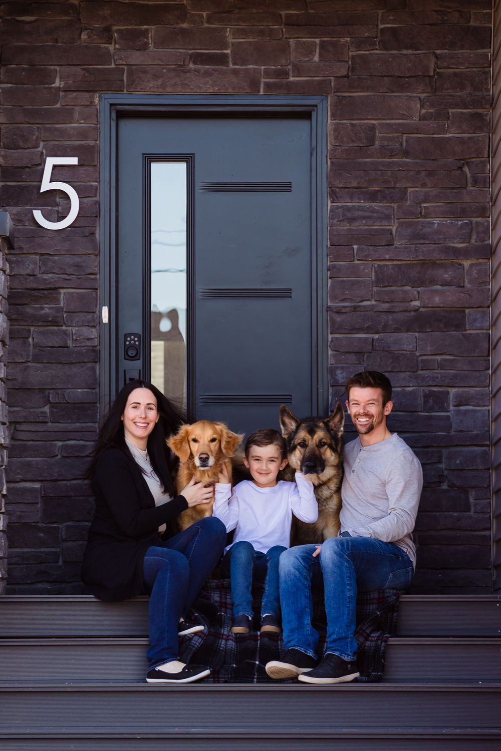 Group relaxing on dark brick porch with two dogs.