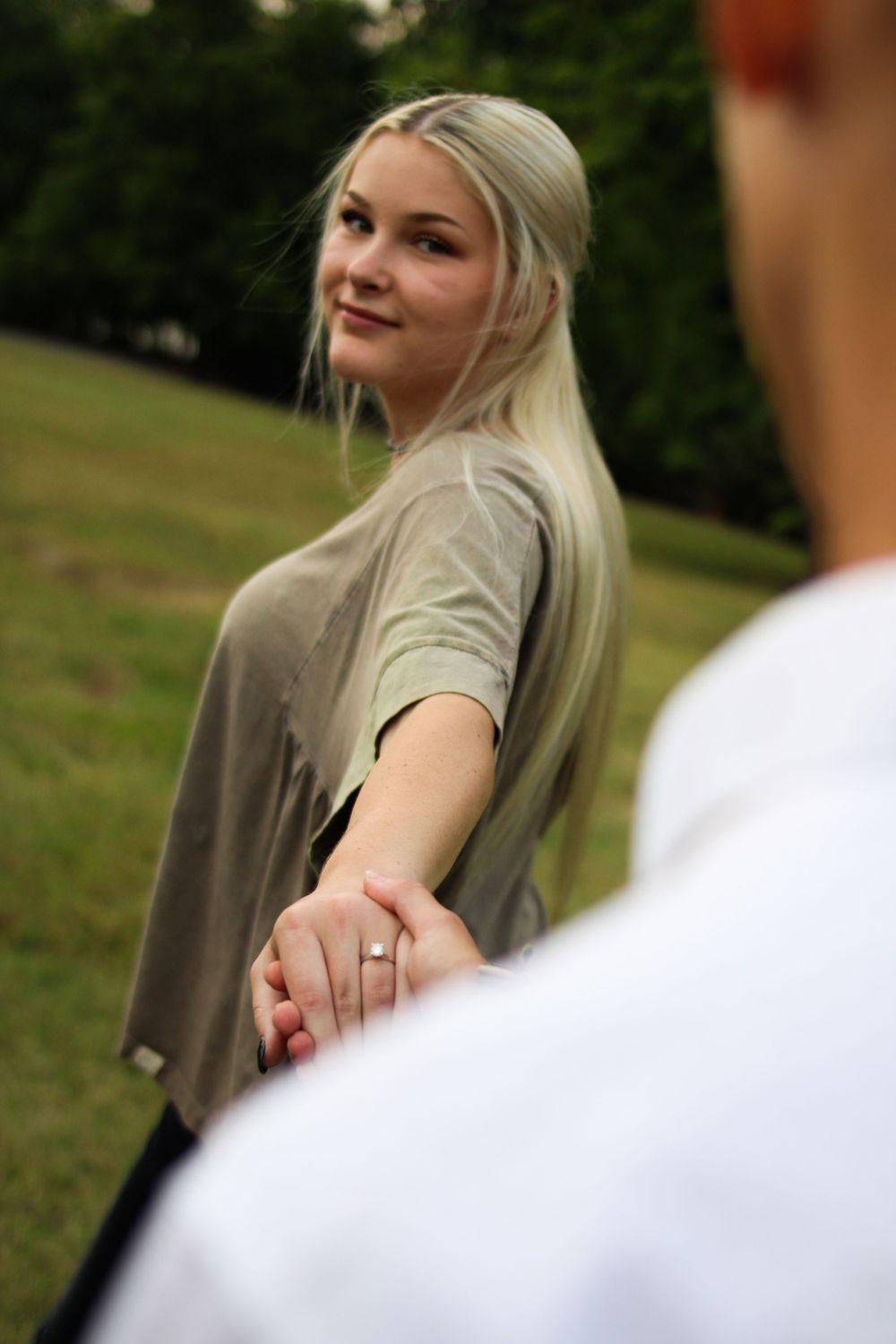 Engagement photo showing ring with couple in outdoor setting.