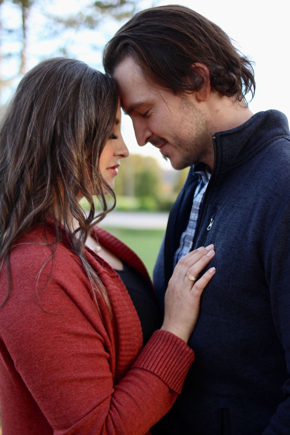 Couple in red and navy sweaters sharing intimate moments outdoors.